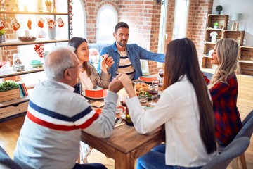 Beautiful family meeting smiling happy and confident. Praying taking hands before eating roasted turkey celebrating Christmas at home