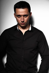 Fototapeta premium Sexy successful young man looking serious in black shirt on grey studio background. Closeup
