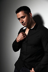 Sexy brutal man looking serious in black shirt on grey studio background. Closeup