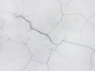 Close-up of a cracked concrete wall painted in white