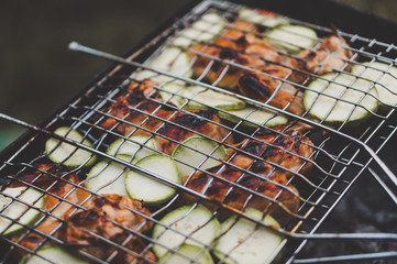 Close-up of chicken and zucchini roasted over the fireplace. Meat and vegetable outdoor grilling at the picknick. Selective focus