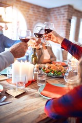 Beautiful group of people meeting smiling happy and confident. Eating roasted turkey and toasting with cup of wine celebrating Thanksgiving Day at home
