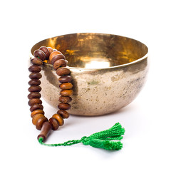 Closeup of a singing bowl and a japamala on a white backround