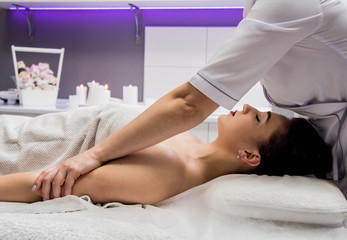 Fototapeta premium Beautiful young woman enjoying massage in spa salon. Cosmetology