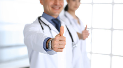 Group of doctors showing thumbs up. Perfect medical service in clinic. Happy future in medicine and healthcare concept