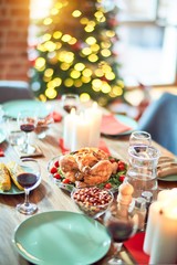 Setting of christmas table on festive holidays, full of traditional food with turky and delicious meals around the tree lights and decoration