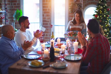 Beautiful family smiling happy and confident. Showing roasted turkey and applauding celebrating Christmas at home