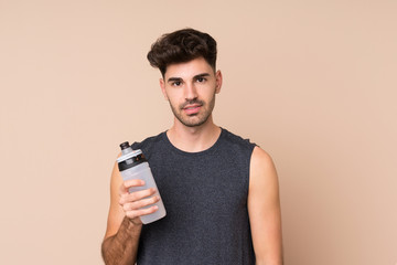 Young sport man over isolated background with sports water bottle