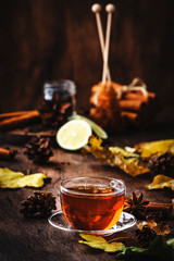 Autumn hot black tea in glass cup, old wooden table background, selective focus