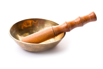 Closeup of a singing bowl and its mallet on a white backround