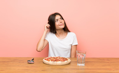 Young woman with a pizza having doubts and with confuse face expression