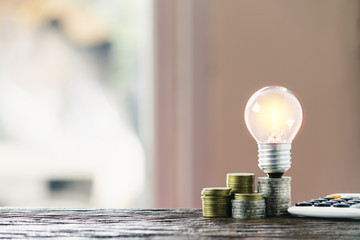 Accounting concept with coins, light bulb and calculator on table.