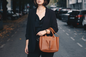 street style 2019, attractive woman wearing a satin top, black blazer and a tan brown tote bag, crossing the street. fashion outfit perfect for fall.