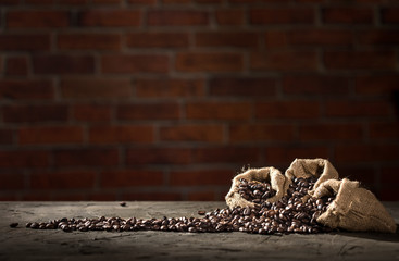 Sacks with coffee beans on a red brick wall background with copy space