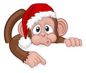 A Christmas monkey animal cartoon character in a Santa hat behind a sign peeking over a sign and pointing at it