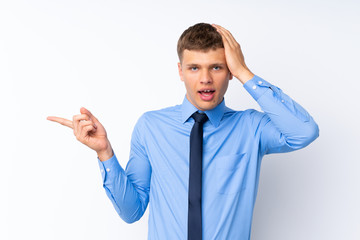 Young handsome businessman surprised and pointing finger to the side