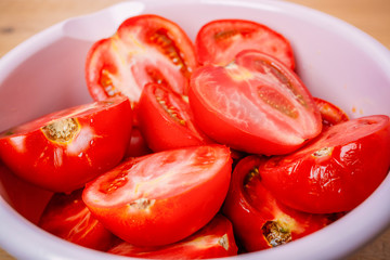 Tomato slices in a bowl on a wooden background