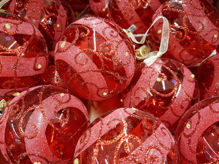 A pile of red glass striped Christmas balls with ornament.