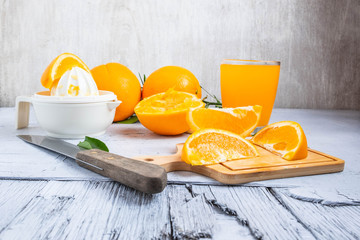 Squeezed orange juice and fresh oranges fruits on white wooden table.Homemade