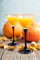 Autumn cocktail with pumpkin and orange juice in martini glass on the rustic background. Selective focus. Shallow depth of field.