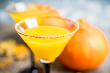 Autumn cocktail with pumpkin and orange juice in martini glass on the rustic background. Selective focus. Shallow depth of field.