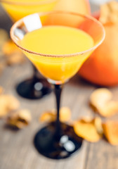Autumn cocktail with pumpkin and orange juice in martini glass on the rustic background. Selective focus. Shallow depth of field.