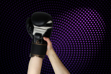 winner’s boxer hand raised in black boxing glove, closeup on dark purple background, copy space,...