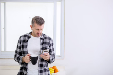 Caucasian man holding coffee while using a phone