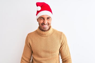 Young handsome man wearing christmas and turtleneck sweater over isolated background winking...