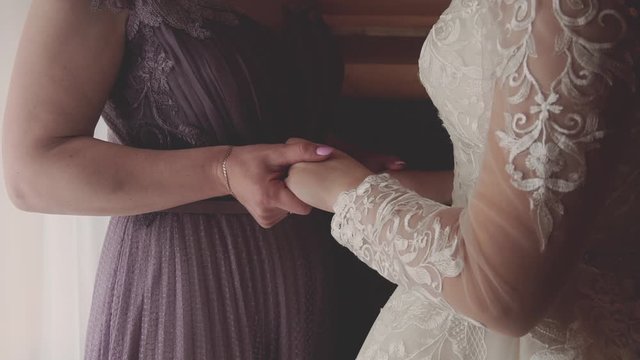 mom and bride hold each other's hands