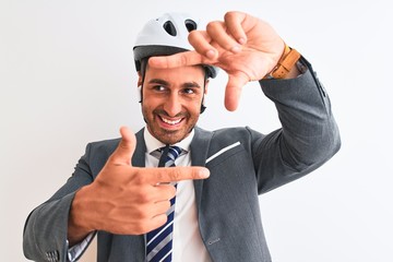 Young handsome business man bike helmet and wireless earphones over isolated background smiling making frame with hands and fingers with happy face. Creativity and photography concept.