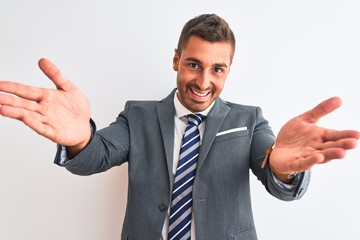 Young handsome business man wearing suit and tie over isolated background looking at the camera smiling with open arms for hug. Cheerful expression embracing happiness.