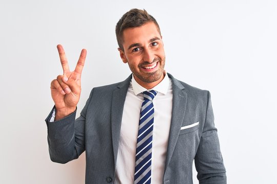 Young handsome business man wearing suit and tie over isolated background smiling looking to the camera showing fingers doing victory sign. Number two.