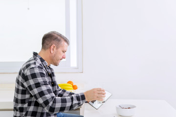 Caucasian man using a tablet during breakfast