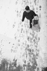 Blurry woman walking while pulling a shopping trolley bag during snowfall, high angle view
