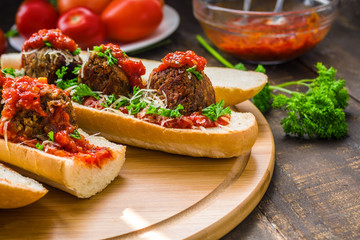 homemade vegatrian sandwiches with lentil meatballs grated cheese tomato fresh parsley sauce on woode ntable close up