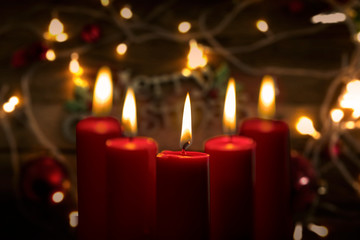 Five burning candles with blurred Christmas light