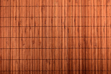 Brown textured wooden bamboo background on a table in warm light, top view