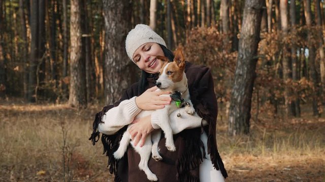 GPS pet tracker helped find a lost dog. Happy woman on a walk in the woods holds in hands a dog of the breed Jack Russell Terrier, petting the dog. Slow-motion shot