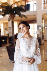 Beautiful bride in fashion wedding dress with a long luxury veil. The stunning young bride is incredibly happy. Gorgeous bride with wedding hairstyle, make-up and elegant white wedding dress.