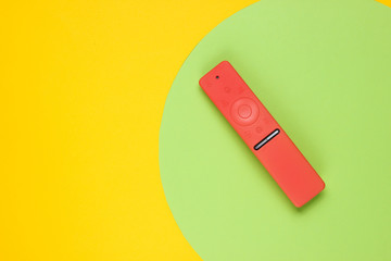 Modern tv remote in a case on colored paper background with geometric shapes. Top view. Fashion concept
