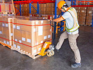 Workers using Hand Pallet Jack Unloading Packaging Boxes on Pallet. Cargo Supply Chain. Shipment...