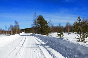 Winter landscape. View of snow-covered trees, snowdrifts and road in the countryside in winter on a frosty Sunny day. Russian nature.