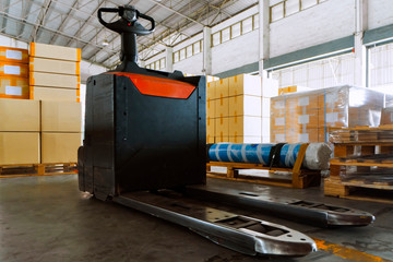 Electric forklift pallet jack with stack package boxes on pallets, interior of warehouse, freight...