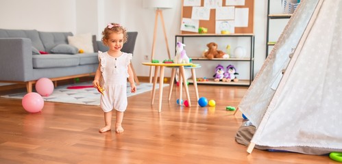 Beautiful caucasian infant playing with toys at colorful playroom. Happy and playful at kindergarten.