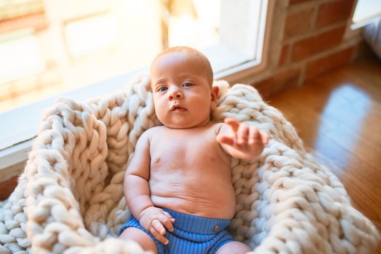 Adorable baby lying down on the floor over blanket at home. Newborn relaxing and resting comfortable