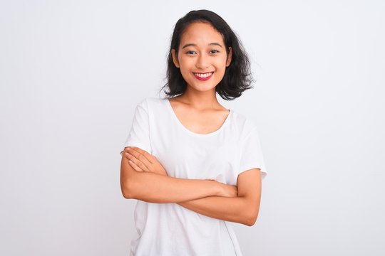Young chinese woman wearing casual t-shirt standing over isolated white background happy face smiling with crossed arms looking at the camera. Positive person.
