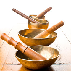 Closeup of four singing bowls and their mallets on a wooden table