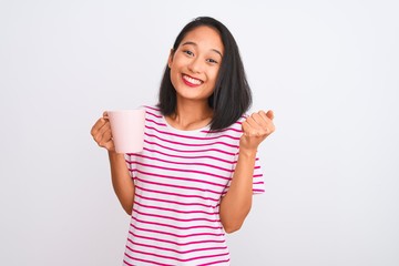 Young beautiful chinese woman drinking cup of coffee over isolated white background screaming proud and celebrating victory and success very excited, cheering emotion