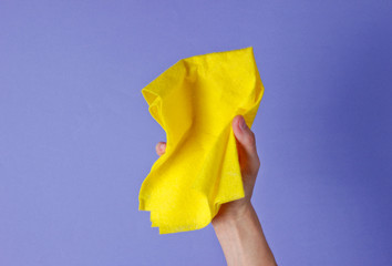 Female hand holds cleaning cloth for on purple background